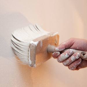 Maler streicht eine Wand mit einem Quast